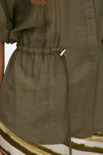 Chemise verte à manches courtes de Vero Moda, avec un cordon de serrage à la taille et un tissu légèrement brillant.