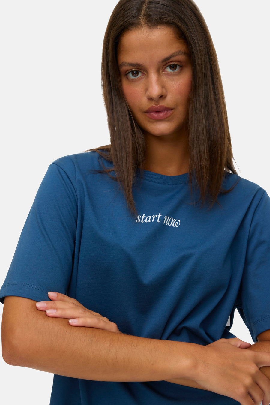 Vrouw met gekruiste armen in blauw T-shirt met de tekst "start now".