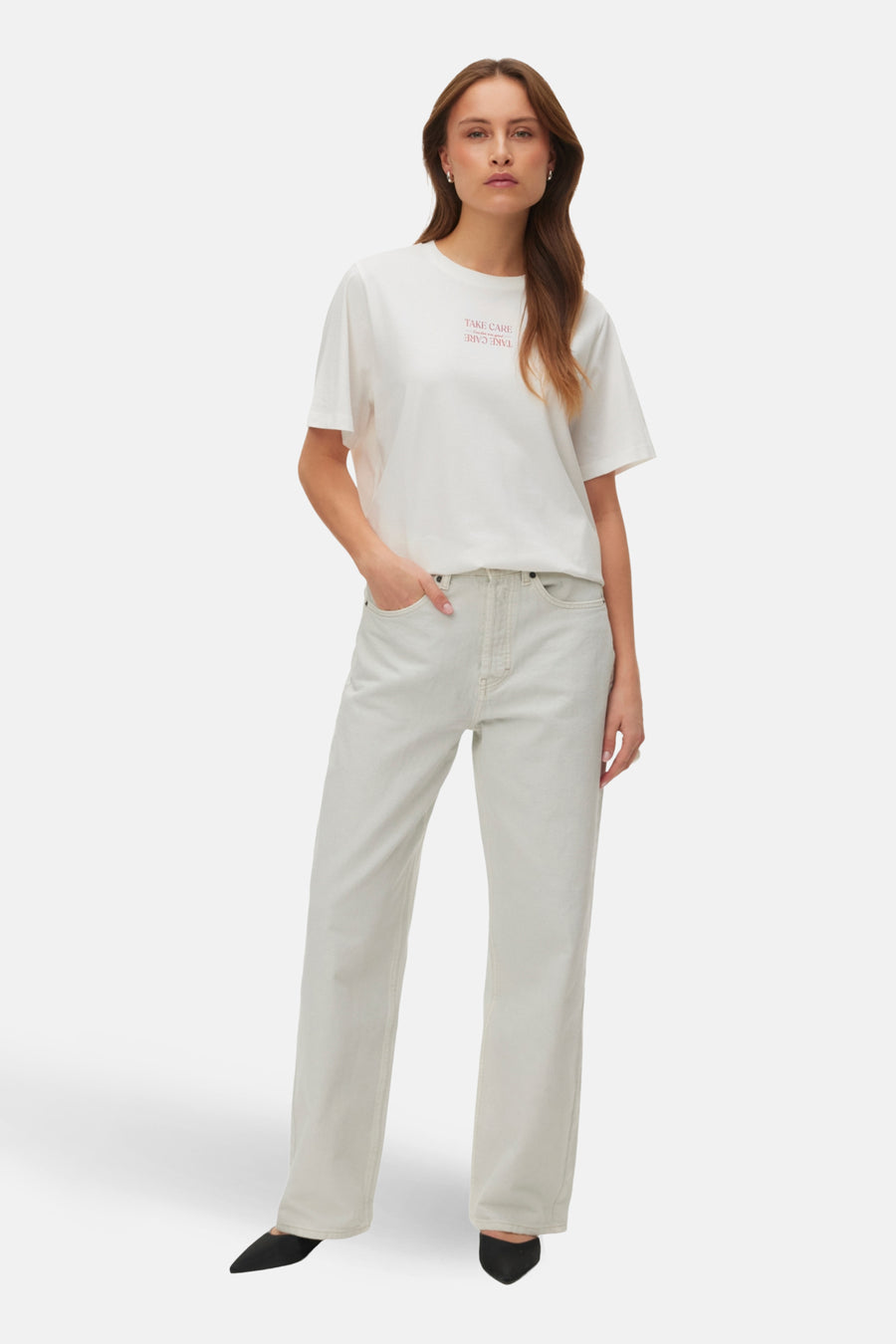 Vrouw met wit T-shirt, lichte jeans en zwarte schoenen.