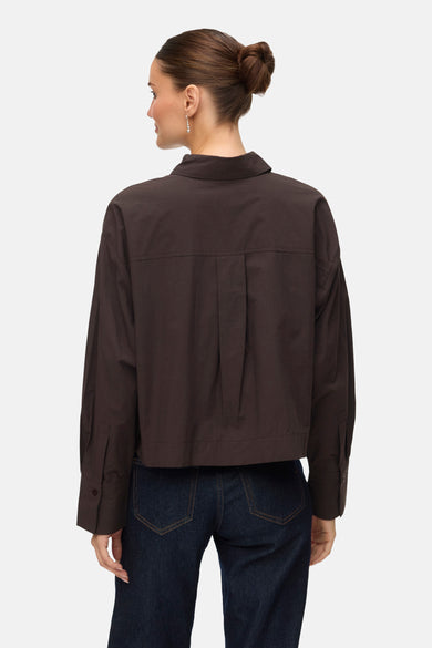 Chemise brune à longues manches de VERO MODA, avec une pliure sur le dos et portée avec un jeans foncé.