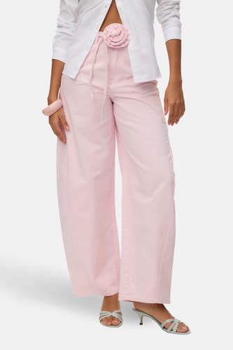 Roze gekleurde jeans van Vero Moda, met wijde pijpen, een stoffen bloem detail en een roze armband.