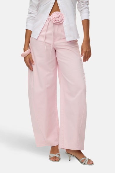 Jeans de couleur rose de VERO MODA, avec jambes larges et poches arrière, combinés avec un chemisier blanc et des talons.
