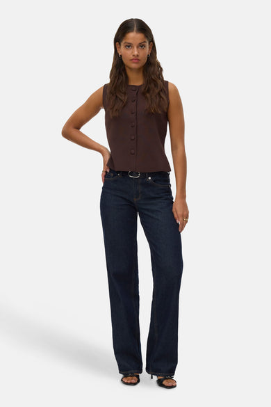 Bruine gilet van VERO MODA®, met knoopsluiting, gecombineerd met een donkere jeans en zwarte hakken.
