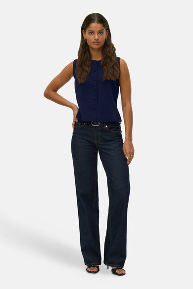 Blauw gilet van Vero Moda, met knoopsluiting, gecombineerd met een donkere spijkerbroek en zwarte hakken.
