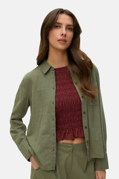 Groen hemd van VERO MODA®, met lange mouwen, gedragen over een rode top en broek.