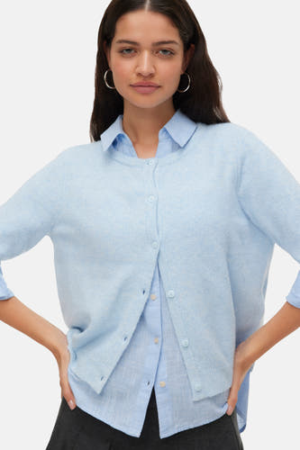 Veste bleue de VERO MODA, portée sur des manches longues sur une chemise bleu clair et une jupe grise foncée.