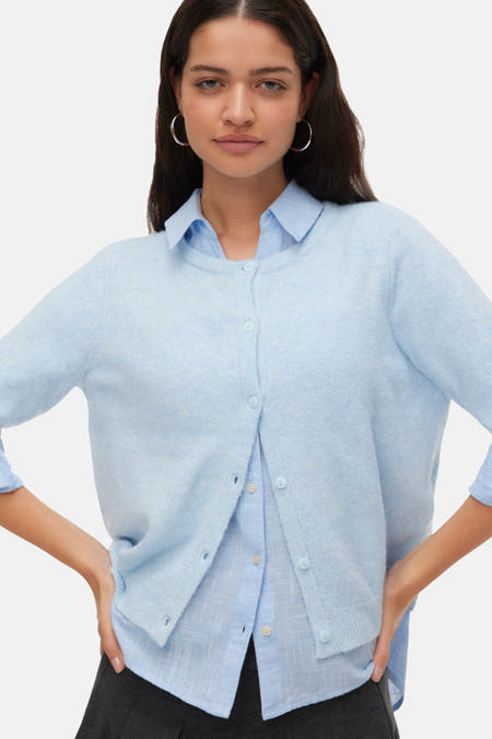 Blauw vest van VERO MODA, gedragen over een blauw geruit overhemd, met zilveren oorringen.
