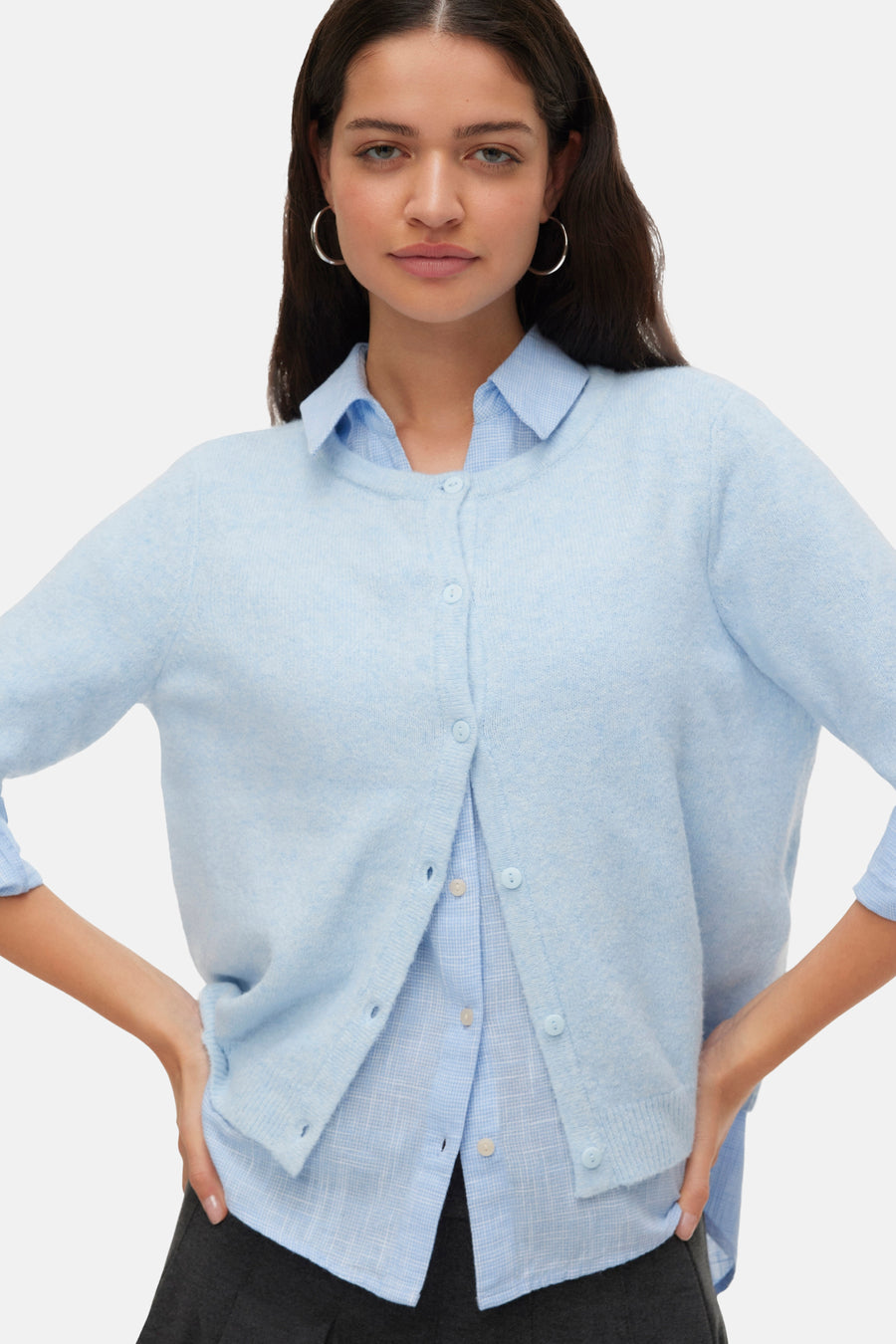 Veste bleue de VERO MODA, portée sur des manches longues sur une chemise bleu clair et une jupe grise foncée.