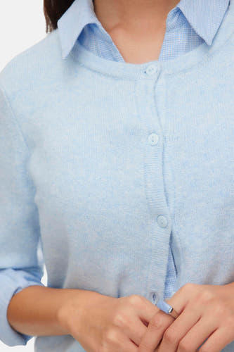 Veste bleue de VERO MODA avec fermeture à boutons, portée sur une chemise bleu clair avec un motif de carreaux subtil.