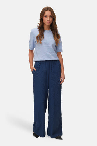 Blauwe broek van Vero Moda, met een geplooide textuur en wijde pijpen, gedragen met een lichtblauwe top.