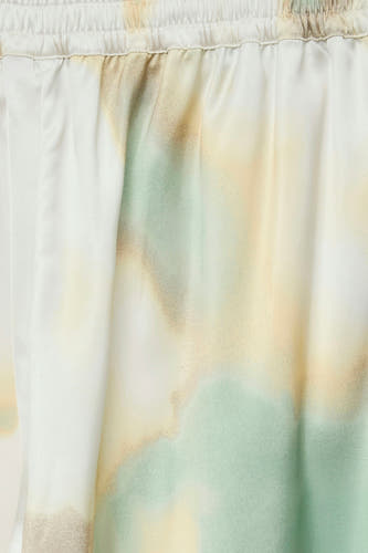 Multicolor colorbroek van VERO MODA® met tie-dye patroon in groen, geel en wit, close-up van stof met elastische tailleband.