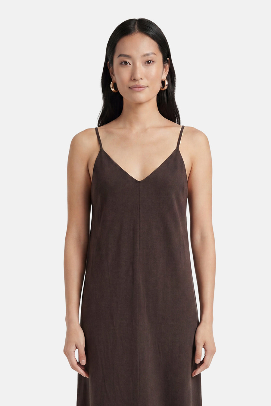 Robe marron sans manches VERO MODA® avec col en V et fines bretelles, portée par une femme avec des boucles d'oreilles dorées.