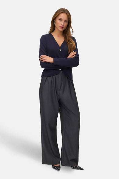 Blauw gilet van VERO MODA®, met lange mouwen, knoopsluiting en gedragen met een grijze, wijd uitlopende broek en puntige pumps.
