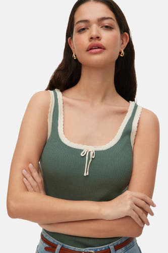 Haut côtelée verte de VERO MODA® avec bord festonné beige, portée par une femme, vue de dos, avec un jean.