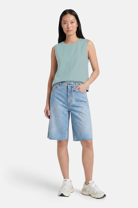 Groene mouwloze blouse van VERO MODA® met ronde hals en lichte textuur, gedragen met lichtblauwe denim shorts en witte sneakers, front view.