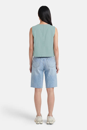 Groene mouwloze blouse van VERO MODA®, achterzijde met rits, gestructureerd materiaal, gekenmerkt door minimalistische stijl, gedragen met lichtblauwe denim shorts en witte sneakers.