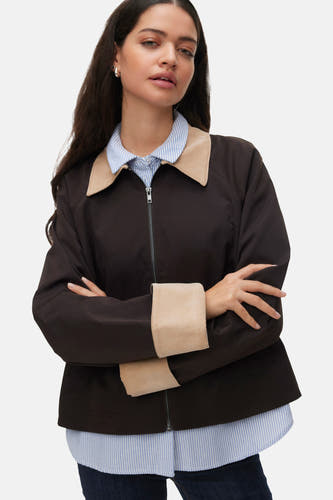 Bruine korte jas van VERO MODA® met beige kraag en manchetten, gedragen over een gestreept overhemd en donkere jeans.
