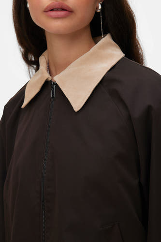 Bruine jas van VERO MODA met beige kraag en zilverkleurige oorbellen.