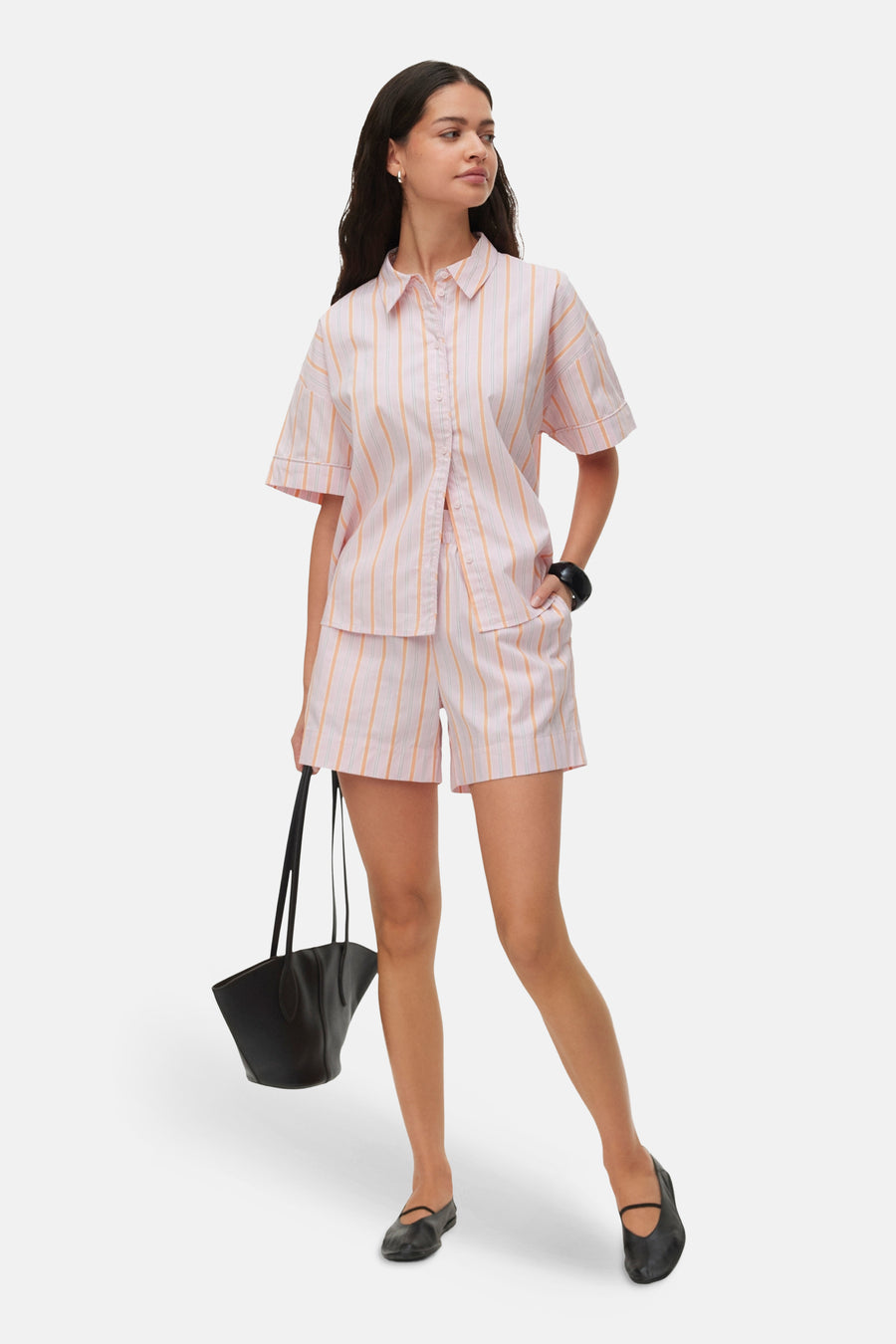 Roze gestreepte blouse met korte mouwen van VERO MODA®, lichte stof, knoopsluiting, model in lifestyle pose met zwarte tas en schoenen