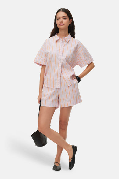Roze gestreepte korte broek van VERO MODA®, lichte stof, comfortabele pasvorm, lifestyle shot met overhemd en zwarte schoenen