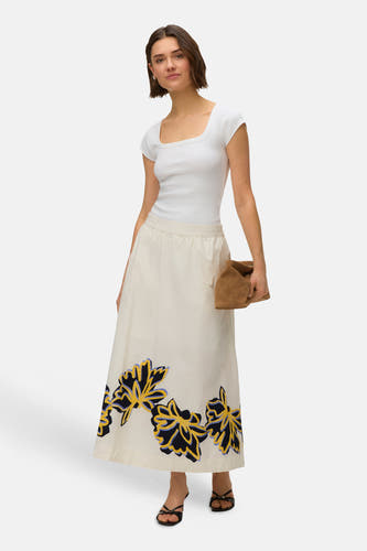 Lange ecru rok van VERO MODA met grote bloemenprint in donkerblauw, geel en lichtblauw aan de zoom, gedragen door een model.