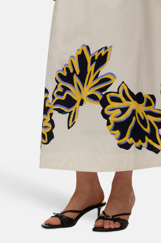 Jupe longue écru de VERO MODA avec motif floral abstrait en noir, jaune et lilas, portée avec des sandales noires à talons.