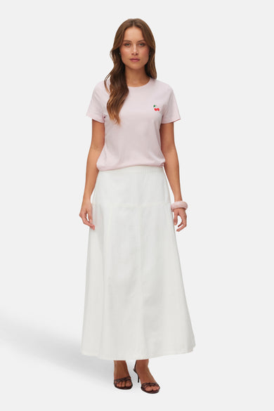 Roze T-shirt met korte mouwen van VERO MODA® met kersendetail, gecombineerd met een witte lange rok en bruine hakken.

