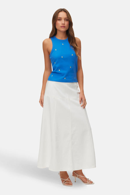 Blauwe singlet tanktop van Vero Moda, met geborduurde citroenmotieven, gecombineerd met een lange witte rok en hakken.
