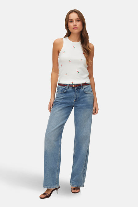 Witte singlet van VERO MODA®, met een kersenpatroon en gecombineerd met een jeans en hakken.