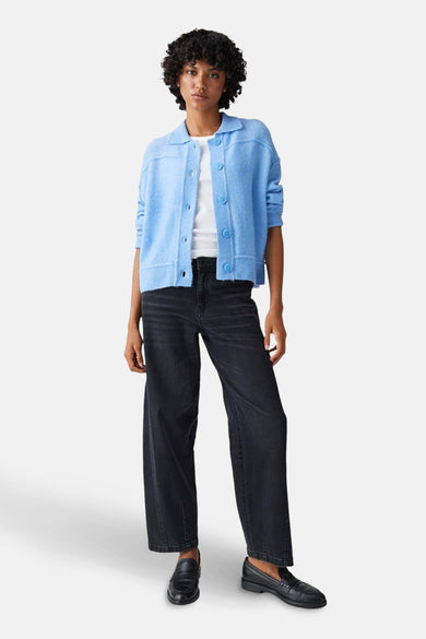 Blauwe trui van OPUS, gedragen met een wit shirt en zwarte jeans met wijde pijpen.