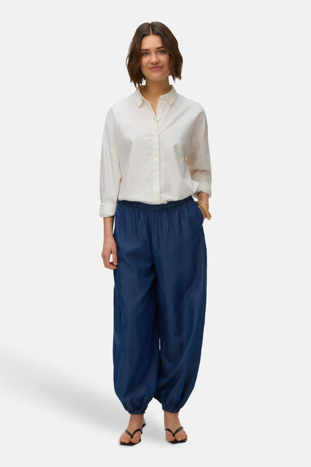 Blauwe broek van VERO MODA, gecombineerd met een wit overhemd en zwarte sandalen.
