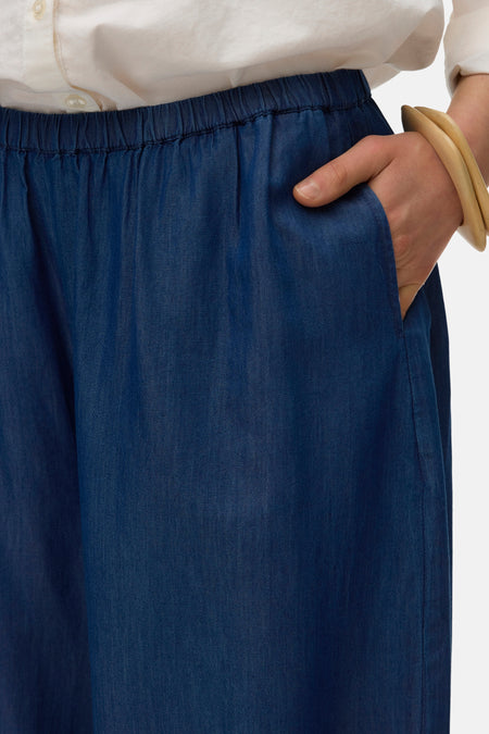 Blauwe broek van VERO MODA, met elastische tailleband en een hand in de zak.
