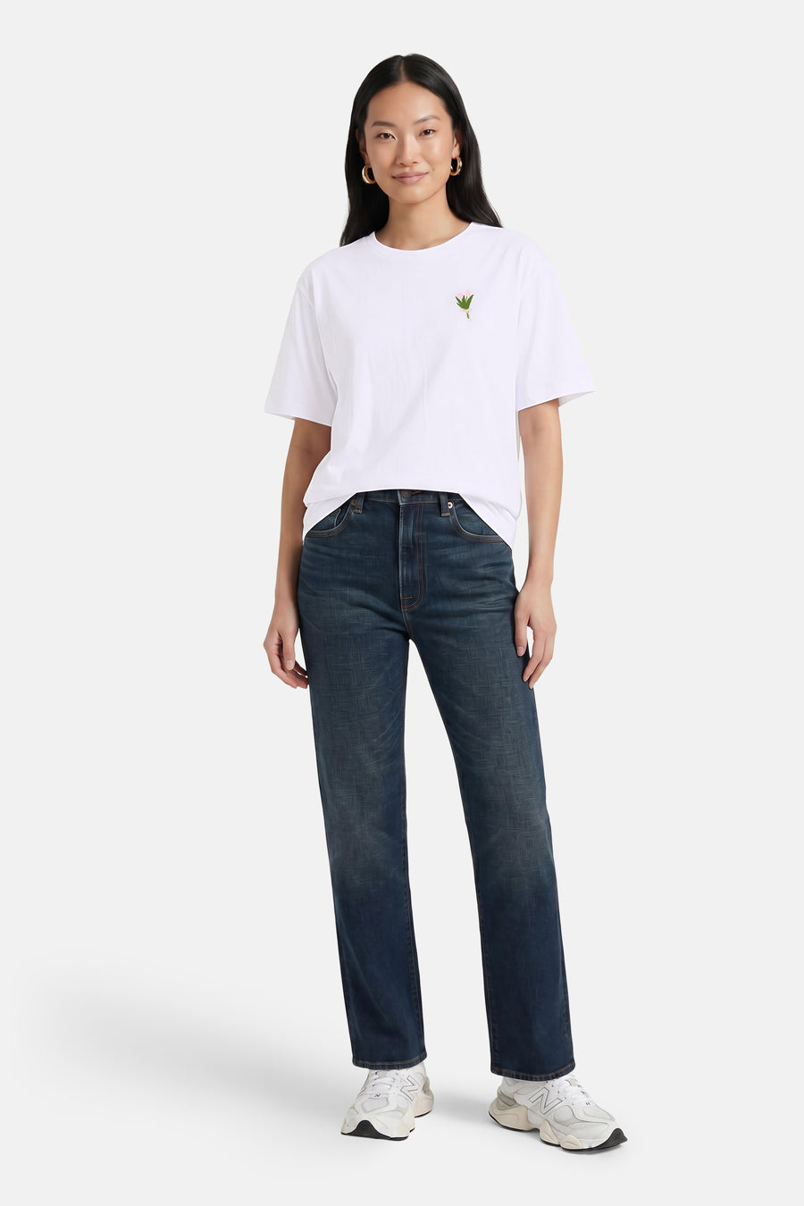 Witte korte mouwen T-shirt met klein roze bloemmotief op borst, van VERO MODA®, gedragen met donkerblauwe jeans en witte sneakers, front view.