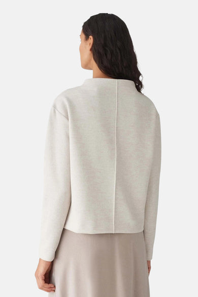Ecru trui met ronde hals van OPUS, rugaanzicht met stiknaad over het midden, gecombineerd met een beige rok.
