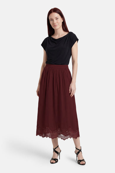 Bordeauxrode rok van VERO MODA® met geplooide taille en kanten zoom, gecombineerd met een zwarte top en zwarte sandalen.