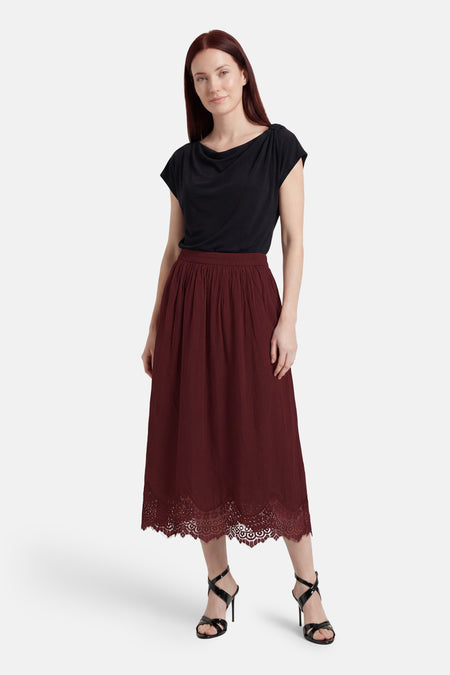 Bordeauxrode rok van VERO MODA® met geplooide taille en kanten zoom, gecombineerd met een zwarte top en zwarte sandalen.