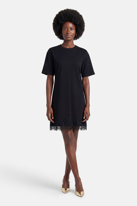 Robe noire à manches courtes de VERO MODA, avec ourlet en dentelle et escarpins dorés, portée par un mannequin.