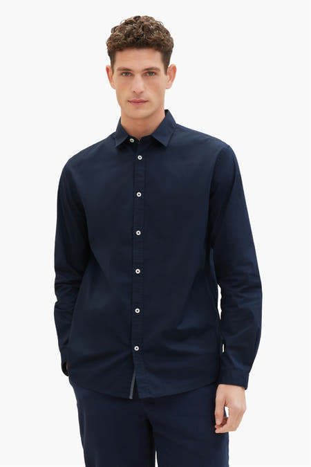 Chemise bleue à manches longues de TOM TAILOR, avec des boutons blancs, associée à un pantalon bleu marine et à des baskets blanches.