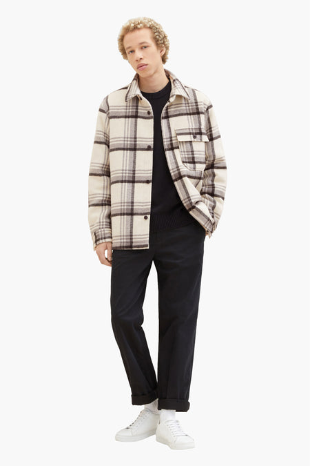 Manteau court noir de TOM TAILOR, avec un gilet à carreaux en blanc cassé, associé à une pantalon noir et des baskets blanches.