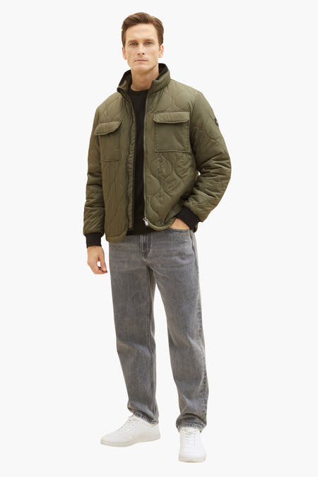 Korte groene jas van TOM TAILOR met gewatteerd ruitpatroon, gedragen met een zwarte trui en grijze jeans.
