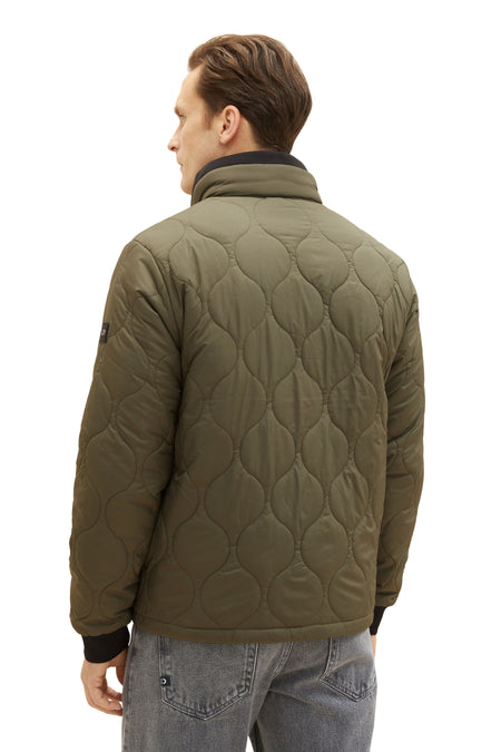 Groene jas van TOM TAILOR, met een gewatteerd ruitpatroon, gezien vanaf de achterkant, met een man in jeans.
