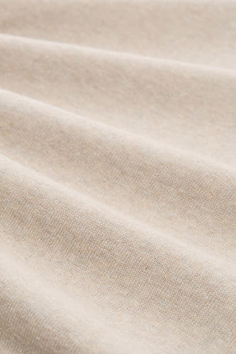Beige trui met ronde hals van TOM TAILOR, close-up van de zachte gebreide textuur in plooien.
