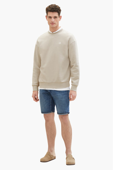Denim jeansshort in donkerblauw, van TOM TAILOR, gecombineerd met een beige sweatshirt en suède muiltjes.