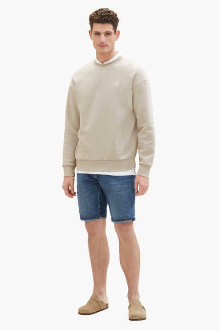 Denim jeansshort in donkerblauw, van TOM TAILOR, gecombineerd met een beige sweatshirt en suède muiltjes.