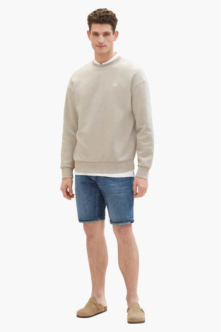 Donkerblauwe jeansshort van TOM TAILOR, gedragen met een beige sweatshirt en suède muiltjes.
