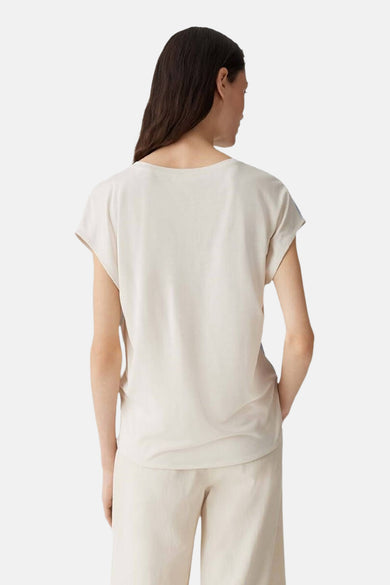 Mouwloze lichtblauwe blouse van OPUS, gezien van achteren en gecombineerd met een beige broek.

