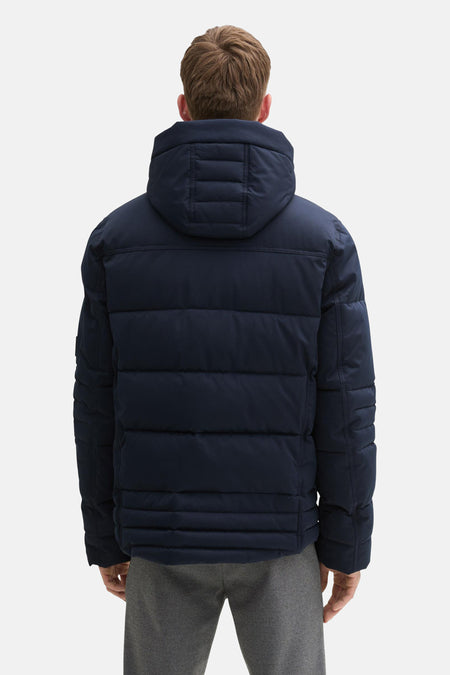 Blauwe korte jas van TOM TAILOR, gezien van achteren, met een capuchon en grijze broek.
