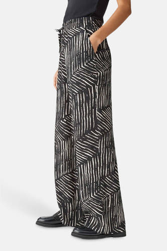 Pantalon noir OPUSUS un motif graphique noir et blanc et des jambes larges, en vue latérale.