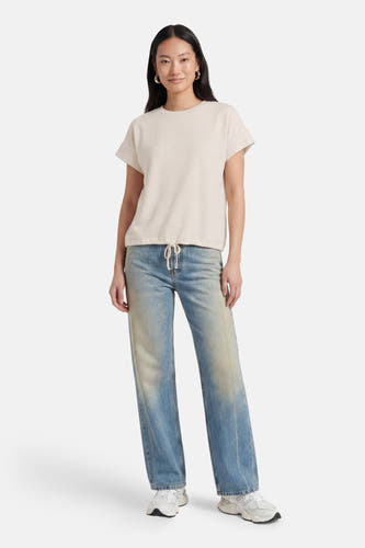 Beige korte mouwen T-shirt van OPUS met wafeltextuur, voorzien van trekkoord aan de zoom, gedragen met lichtblauwe jeans en witte sneakers.