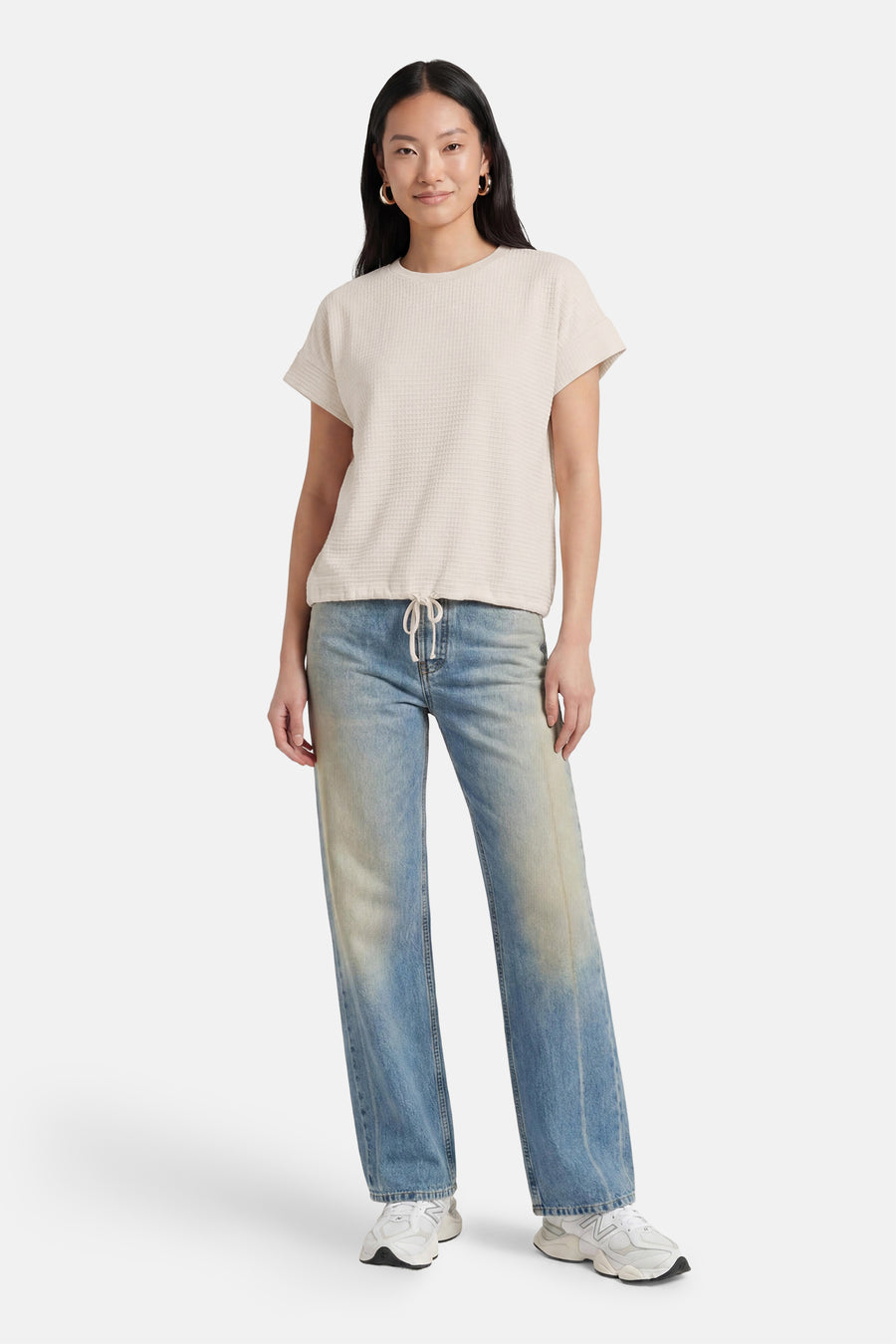 Beige korte mouwen T-shirt van OPUS met wafeltextuur, voorzien van trekkoord aan de zoom, gedragen met lichtblauwe jeans en witte sneakers.